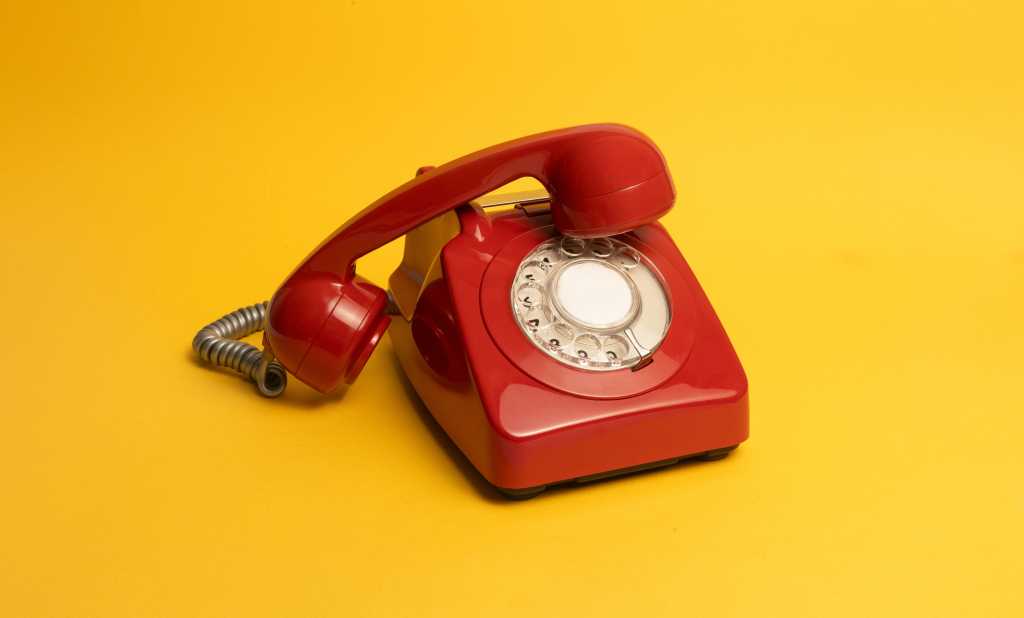 bright red vintage rotary phone on vibrant yellow background